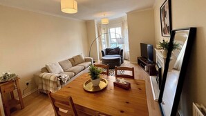 A compact living space with a dining table, sofa, and a television. - City Centre Home - Away from Home (Edinburgh)