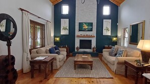 Ein Wohnzimmer mit Kamin, zwei Sofas, einem Couchtisch, einer Lampe und einer Gitarre.
