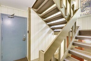 A spiral staircase with carpeted steps and a blue door with a lock. - Walk to Weirs Beach! Family Escape w/ Balcony (Laconia)