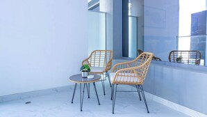 Un balcón con dos sillones de mimbre, una mesita y una planta en maceta.