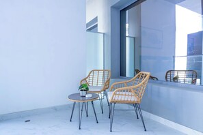 Ein Balkon mit zwei Korbstühlen, einem kleinen Tisch und einem Blumentopf.