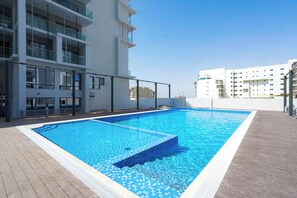 Ein Dachpool mit einer gefliesten Kante, umgeben von modernen Gebäuden mit Balkonen.