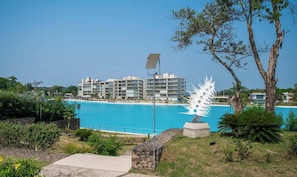 Un complex turístic amb piscina, edificis moderns i una escultura singular.