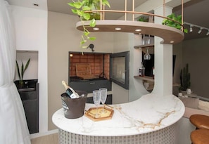 A modern kitchen with a marble countertop, a hanging plant, and a bar area with a bottle of champagne. - Corporate Stays Aqua (Altos)