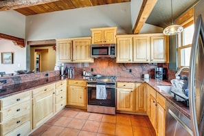 Eine Küche mit Holzausstattung, einem Edelstahlbackofen, einer Mikrowelle und einer Arbeitsplatte aus Granit.