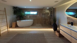 A modern bathroom with a freestanding bathtub, a shower, and a large mirror.