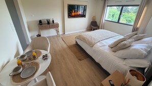 A modern bedroom with a large bed, a dining table, and a TV.