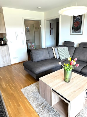 A modern living room with a grey sofa, a wooden coffee table, and a vase of tulips. - Kathrin's Holiday Apartment (Bad Waldsee)