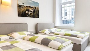 Habitación de hotel con dos camas, un ventanal grande y un cuadro colgado en la pared.