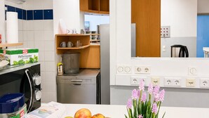 Cocina moderna con lavavajillas, un fregadero y una estufa. Hay estantes con utensilios de cocina y una tetera.