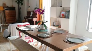 A dining area with a wooden table set for four, a bench, a piano, and a potted plant. - Family home on the edge of the forest (Salles)
