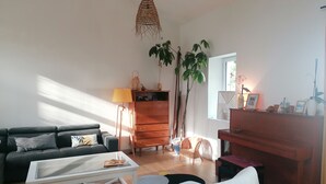 A living room with a sofa, coffee table, dresser, and plants. - Family home on the edge of the forest (Salles)