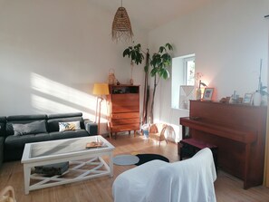 A living room with a sofa, coffee table, dresser, and plants. - Family home on the edge of the forest (Salles)