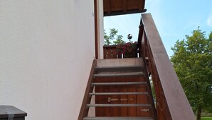 Eine Holztreppe mit Metallgeländern, die zu einem überdachten Außenbereich führt.