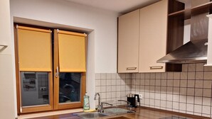 Eine Küche mit eingebautem Backofen, Spüle und einem Fenster mit gelben Rollos.