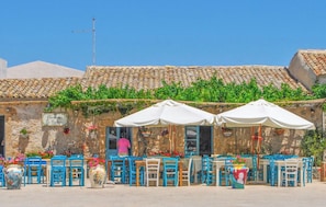 A traditional outdoor café with stone walls, terracotta tiles, and blue chairs. - Villa in Noto with 3 bedrooms sleeps 7 (Noto)