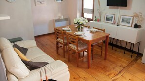 A dining area with a wooden table, chairs, and a white sofa. - Grandparents' Cottage, 15 min from Lake Garda, View of Monte Baldo, Free Parking (San Zeno)