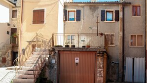 A building with a staircase leading to a gated entrance, a small garden area with potted plants, and a clear blue sky. - Grandparents' Cottage, 15 min from Lake Garda, View of Monte Baldo, Free Parking (San Zeno)