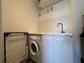 A compact laundry area with a washing machine, a drying rack, and a sink. - La Casa di Luigi by Geco Vacation Rentals (Marina Di Ragusa)