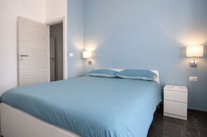 A bedroom with a bed, bedside tables, and wall-mounted lamps. - La Casa di Luigi by Geco Vacation Rentals (Marina Di Ragusa)