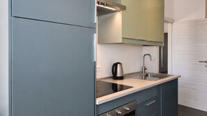 Uma cozinha compacta com fogão embutido, pia e chaleira.