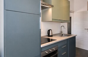 A compact kitchen with a built-in stove, a sink, and a kettle. - La Casa di Luigi by Geco Vacation Rentals (Marina Di Ragusa)