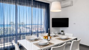 Uma zona de refeições moderna com uma mesa posta para quatro pessoas, uma garrafa de vinho e uma taça de fruta.