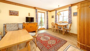 A cozy room with a wooden dining table, chairs, a television, and a cabinet. - "Schneehase" Vacation Rental with Terrace and Mountain View, 50 square meters (Reit im Winkl)