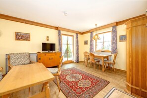 A cozy room with a wooden dining table, chairs, a television, and a cabinet. - Schneehase Vacation Rental, 40 square meters (Reit im Winkl)