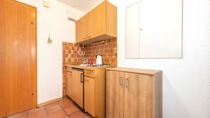 Cozinha compacta com armários de madeira, painel de azulejos e parede branca.