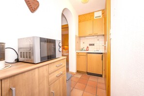 A compact kitchen with wooden cabinets, a microwave, and a toaster. - Auerhahn Vacation Rental, 36 square meters (Reit im Winkl)