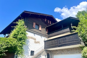 A traditional building with a sign reading 'Landhaus Evelin' and a stone staircase leading to a door. - Auerhahn Vacation Rental with Balcony and Mountain View, 42 square meters (Reit im Winkl)