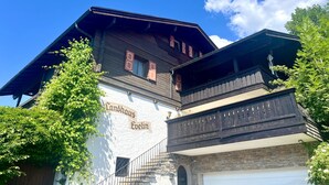 En traditionel træbygning med et skilt der viser 'Landhaus Evelin' og en stentrappe, der fører op til en dør.