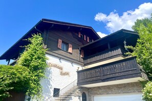 A traditional wooden building with a sign reading 'Landhaus Evelin' and a stone staircase leading to a door. - Auerhahn Vacation Rental with Balcony and Mountain View, 42 square meters (Reit im Winkl)