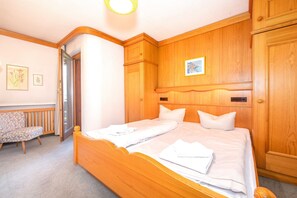 A bedroom with a wooden bed, a chair, and a radiator. - Auerhahn Vacation Rental, 36 square meters (Reit im Winkl)