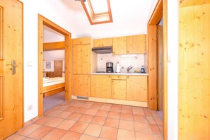 A compact kitchen with wooden cabinets, a built-in stove, and a skylight. - Alpendohle Apartment: Apartment with a View and a Balcony (Reit im Winkl)