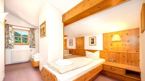 Ein Schlafzimmer mit einem hölzernen Bett, einem Nachttisch, einer Lampe und einem Fenster mit Vorhängen.