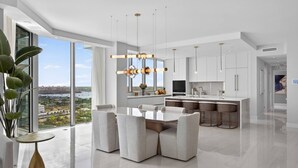 A modern kitchen with a large island, pendant lighting, and a view of the city.