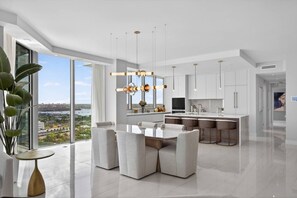 A modern kitchen with a large island, pendant lighting, and a view of the city.