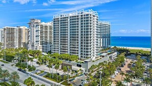 A high-rise hotel with multiple floors, a beach view, and a parking area with palm trees.