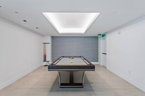 Ein Billardtisch in einem Raum mit Oberlichter, weißen Wänden und einer grauen Akzentwand.