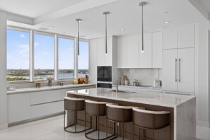 A modern kitchen with a large island, bar stools, and a view of the water.