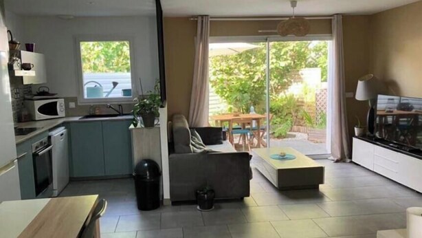 Ett kompakt bostadsutrymme med ett litet kök, en soffa, ett soffbord och en tv.