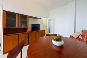 A dining area with a wooden table, chairs, a television, and a cabinet with glass doors. - GuestHost - Sea View Moro Apartment (Montesilvano)