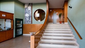 Eine Wendeltreppe mit Holzwand und Spiegel sowie eine Tür mit Hinweisschild.