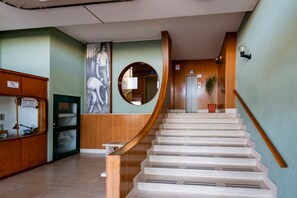 A spiral staircase with a wooden handrail, a wall-mounted mirror, and a door with a sign. - GuestHost - Sea View Moro Apartment (Montesilvano)