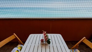 Ein weißer Tisch mit zwei Zimmerpflanzen und einem Stuhl mit gemustertem Sitzkissen.