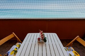 A white table with two potted plants and a chair with a patterned cushion. - GuestHost - Sea View Moro Apartment (Montesilvano)