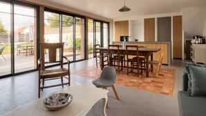Una cocina moderna con armarios de madera, un comedor con mesa y sillas, y grandes puertas correderas de vidrio que dan a un patio exterior.
