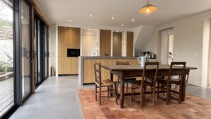 Una cocina moderna con comedor, ventanas amplias y una lámpara en el techo.